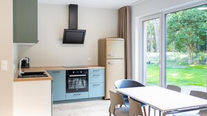 Moderni keittiö, jossa on sisäänrakennettu uuni, vedenkeitin ja litteänäyttöinen televisio.