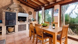 Une cuisine rustique avec un four en briques, des chaises en bois et une table à manger.