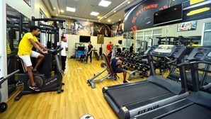 A gym with treadmills, weight machines, and a mirrored wall. - Two Bedroom Apartment Near NMC Sociality Hospital (Dubai)