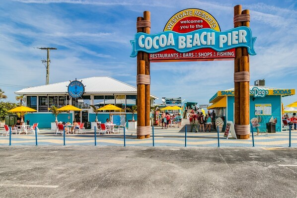 Entrada a un muelle de playa con un letrero que dice 'Cocoa Beach Pier' y 'Westgate Resorts'.