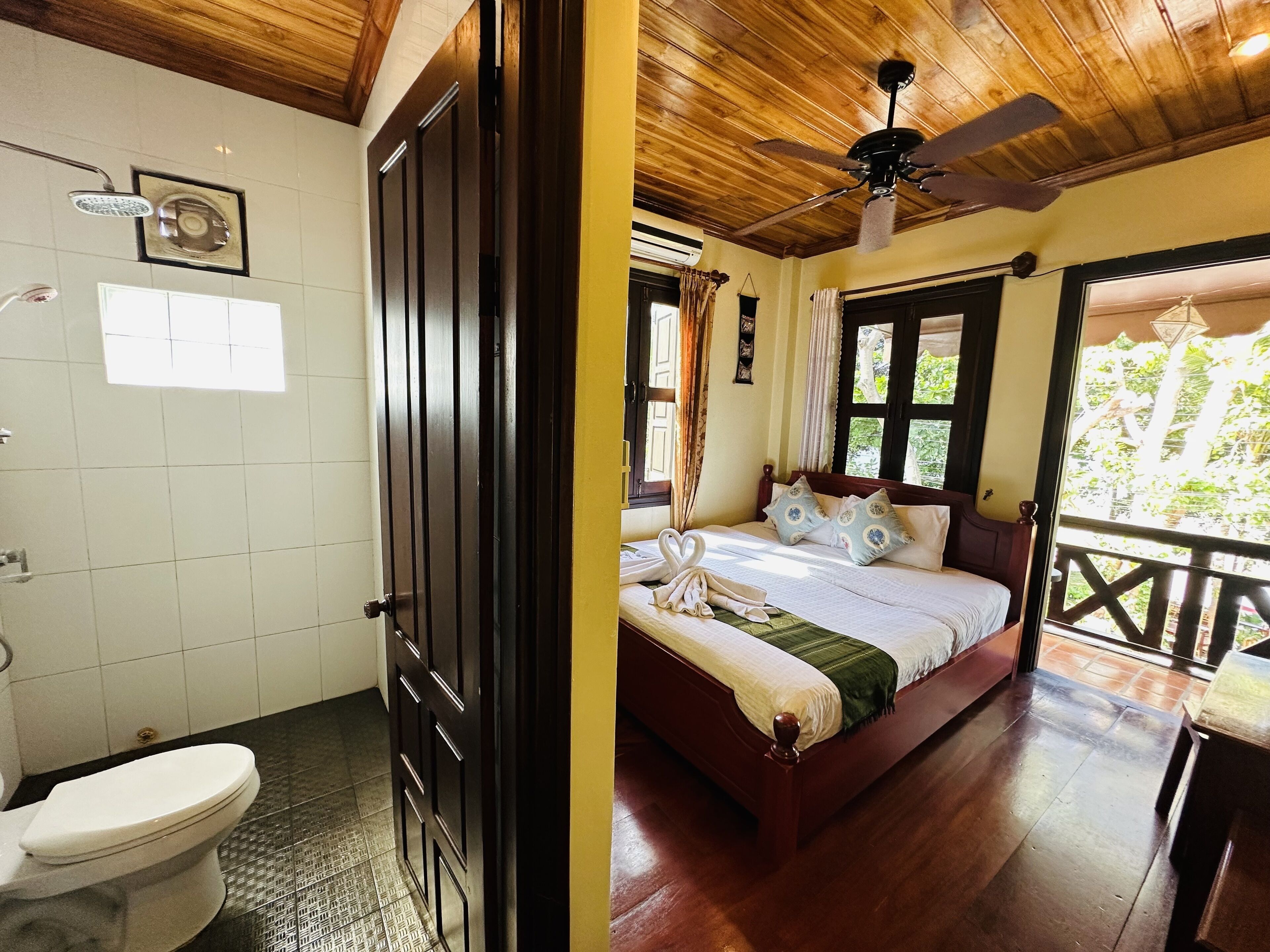 A bathroom with a toilet, shower, and a wooden ceiling.
