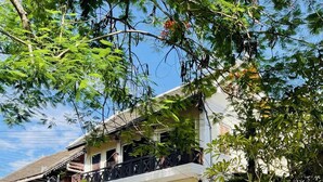 A traditional building with a balcony, potted plants, and a signboard. - Anisa Mekong Riverside Villa (Luang Prabang)