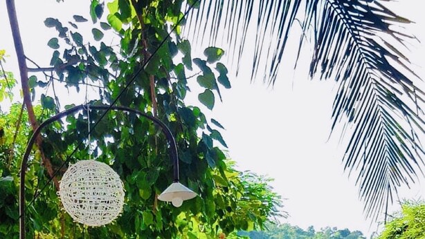 An outdoor seating area with wooden tables and chairs, umbrellas, and a view of a river. - Anisa Mekong Riverside Villa (Luang Prabang)