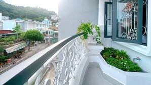 A balcony with a white railing, a potted plant, and a window with decorative iron bars. - Milanesa Hotel & Apartment (Ho Chi Minh City)