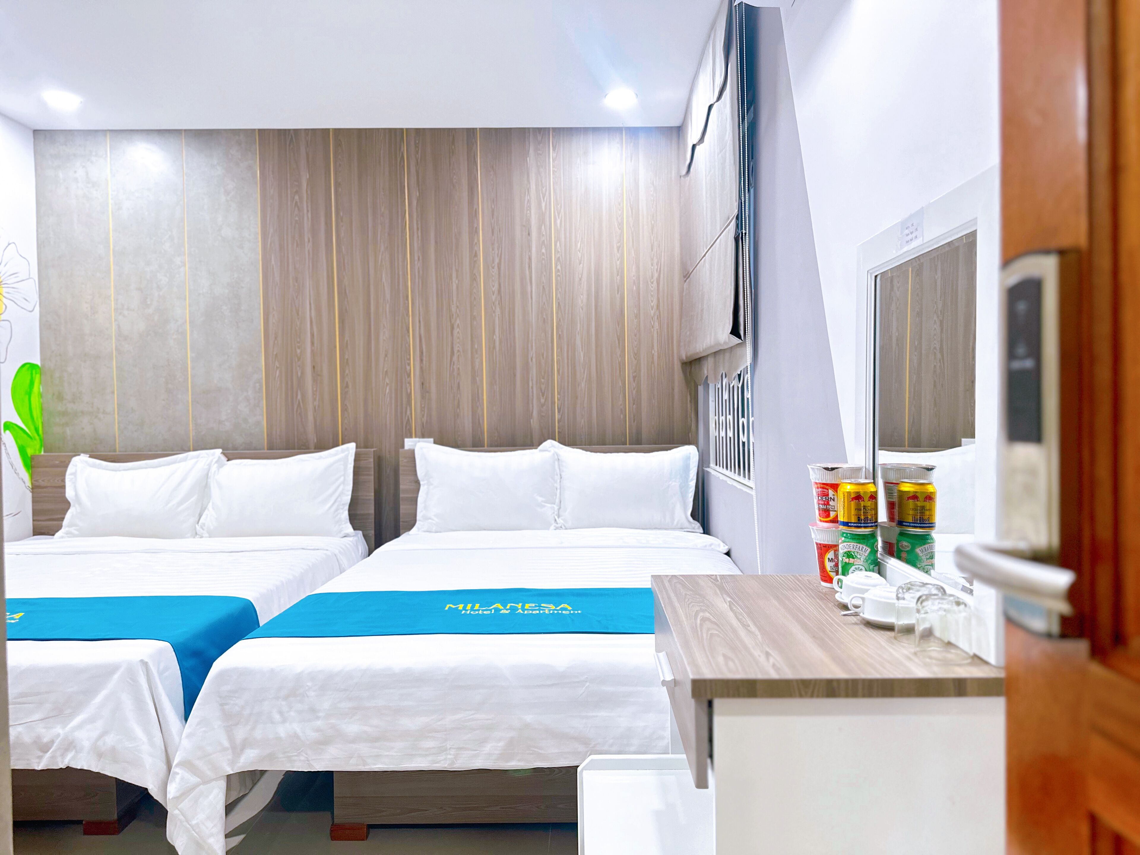 A hotel room with two beds, a wooden headboard, a small table with a mirror, and a minibar.