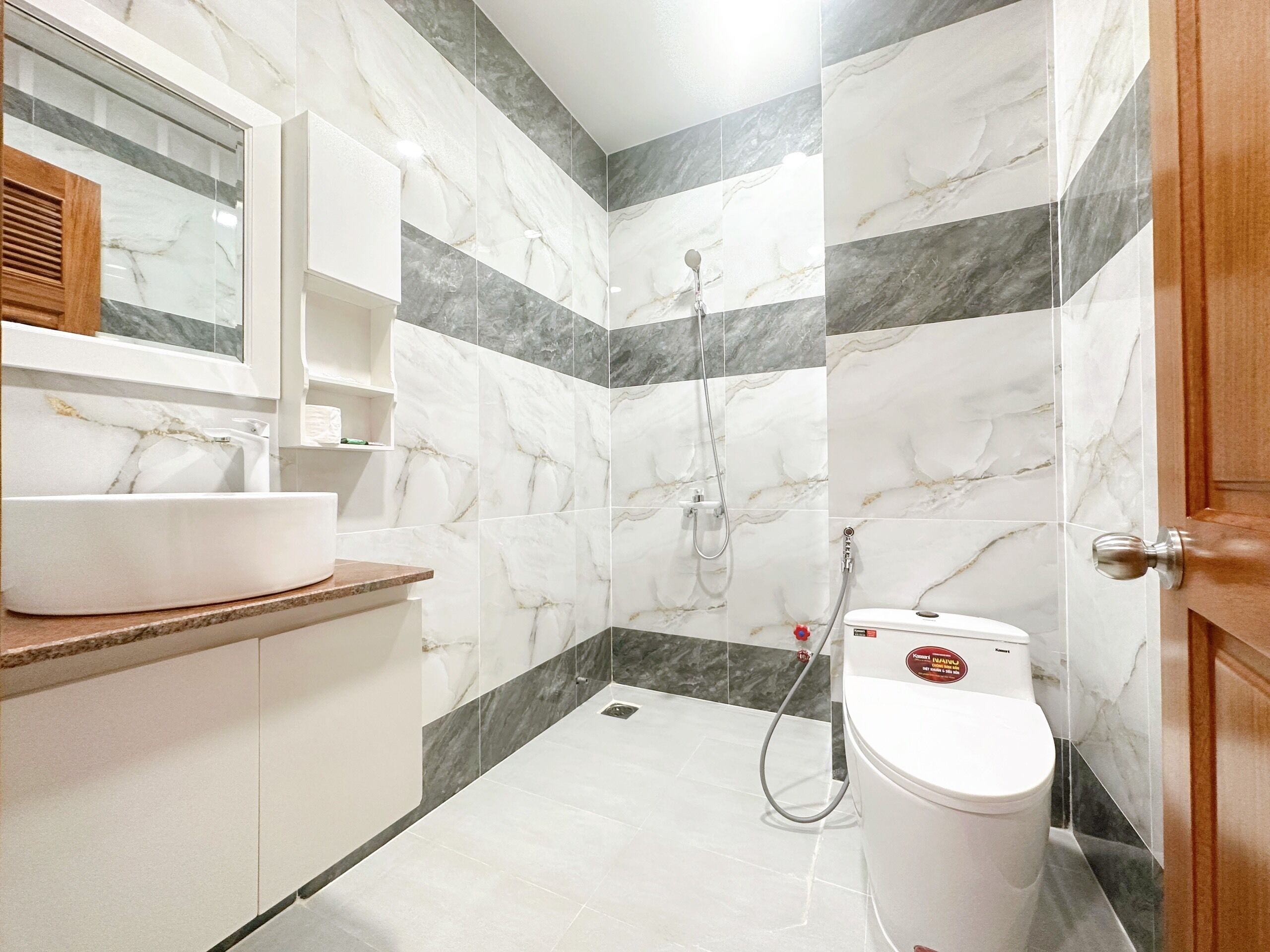 A bathroom with a marble vanity, a toilet, and a shower.