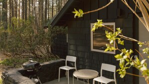 Eine Terrasse mit Grill, zwei Stühlen und einem Tisch.