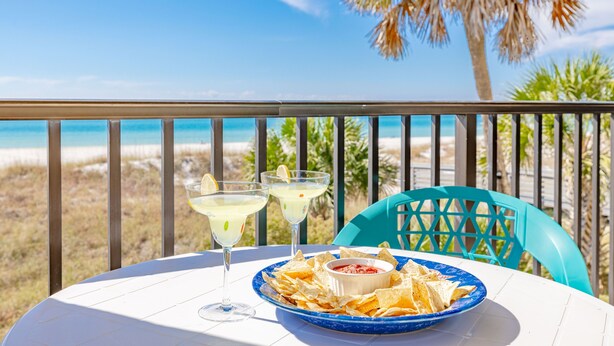 Ein Tisch mit einer blauen Schüssel Nachos, einer Salsa-Schale und zwei Margaritas auf einer weißen Tischdecke.