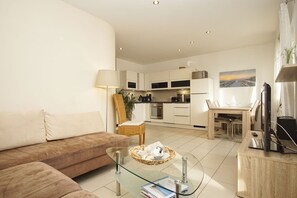 A modern living room with a sofa, a glass coffee table, and a dining area with a table and chairs.
