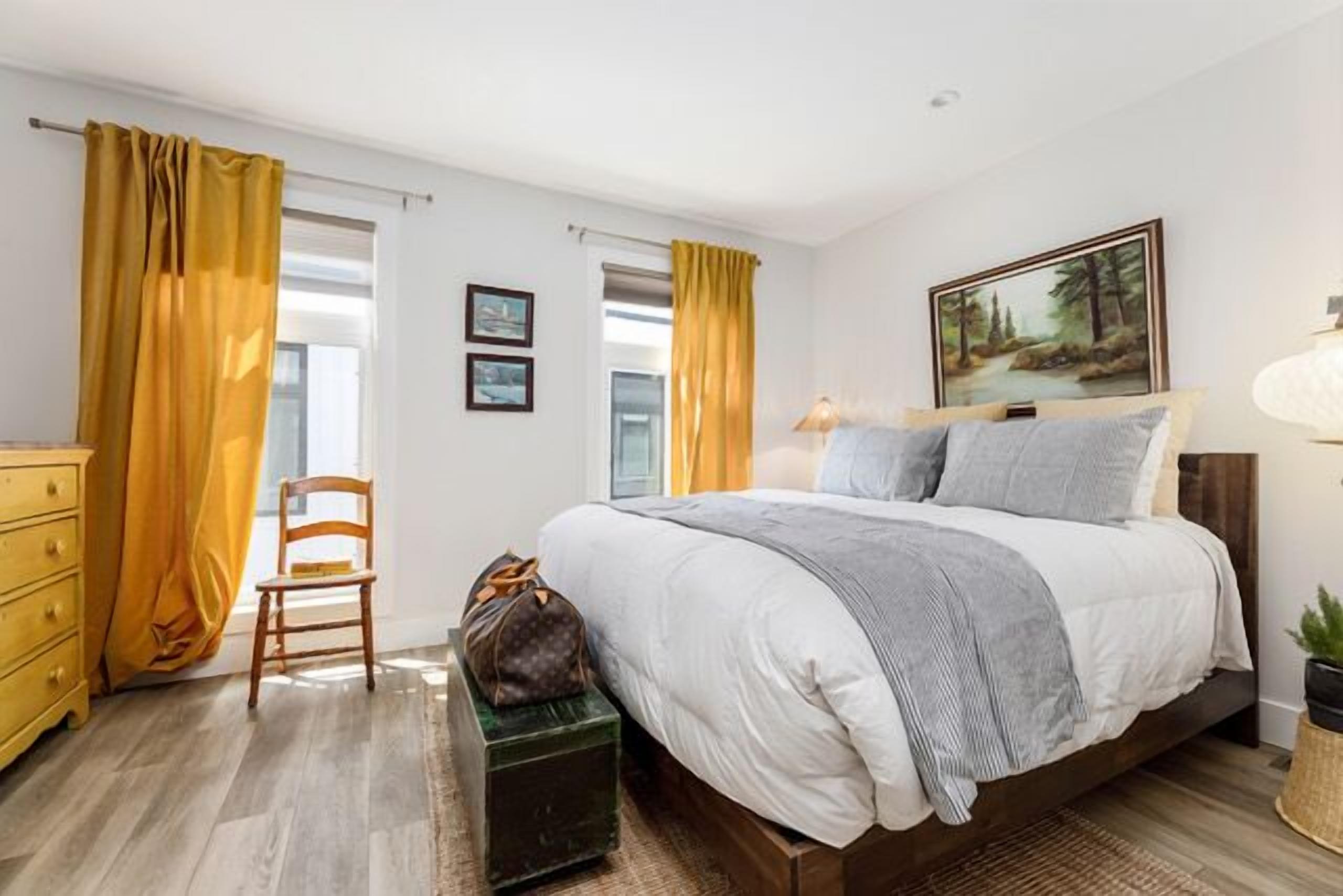A bedroom with a bed, a chair, a dresser, and a painting on the wall.
