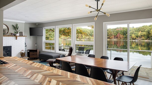 Un espace repas moderne avec une grande table en bois, des chaises noires et une cheminée.