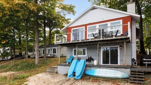 Une maison à deux étages avec un balcon, une allée en gravier et un toboggan aquatique bleu.