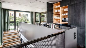 A modern kitchen with a central island, built-in shelves, and a view of greenery outside. - Clean Wiedikon 2BR w/ Storage & W/D, close to Market, by Blueground (Zurich)