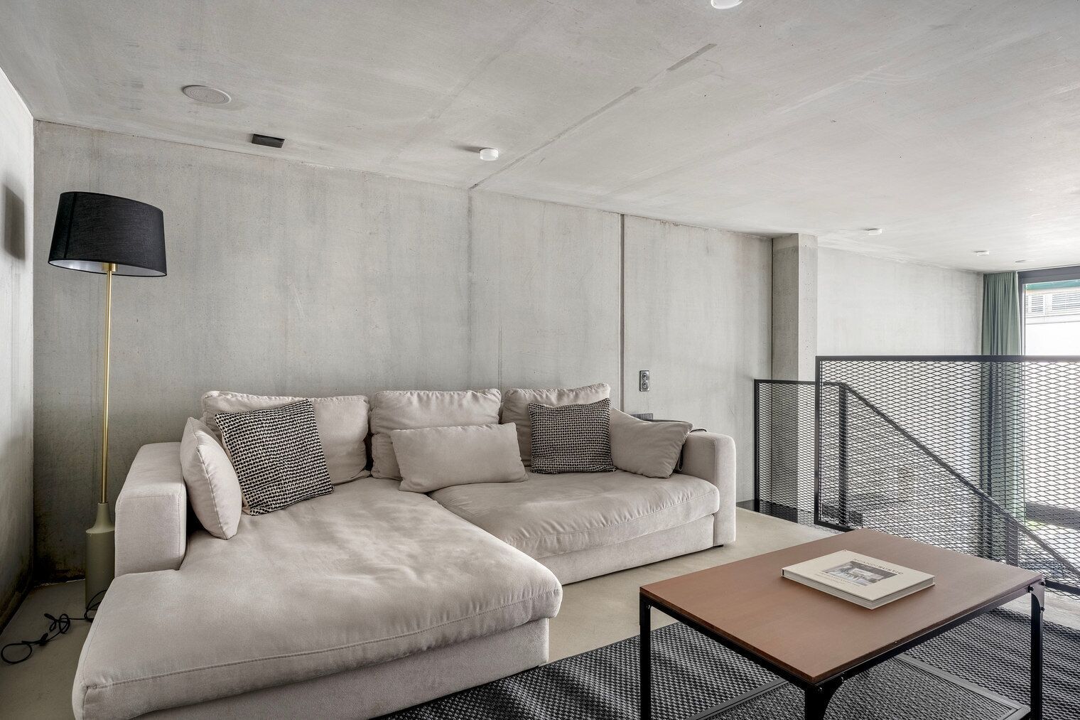 Un salon moderne avec un canapé d’angle, une lampe sur pied et une table basse.