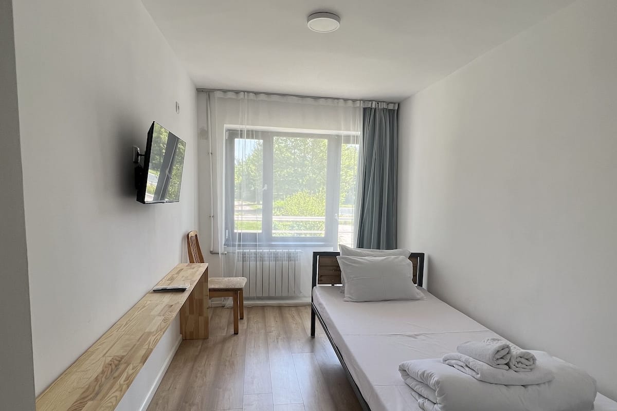Un dormitorio moderno con cama, escritorio y televisión.