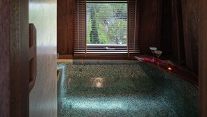 Un cuarto de spa con detalles de madera, un ventanal grande y un piso con textura verdosa.