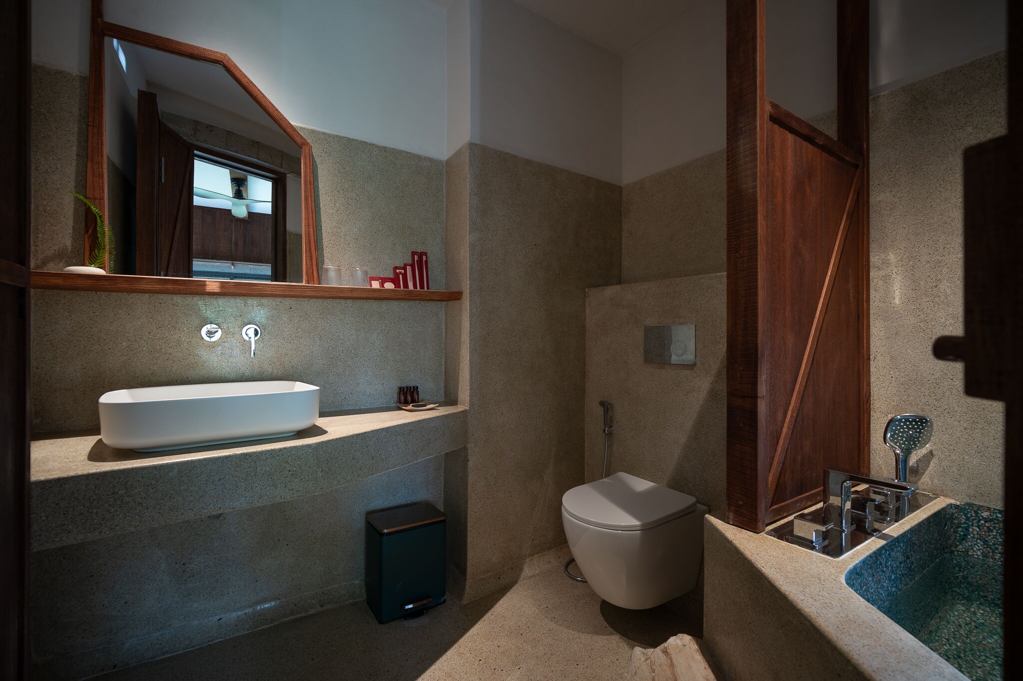 A modern bathroom with a freestanding sink, a toilet, and a shower area.