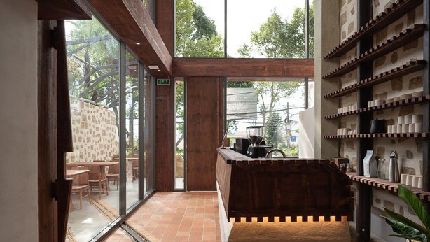 Un interior moderno con un banco de madera, una estación de café y vistas amplias a través de grandes ventanales.