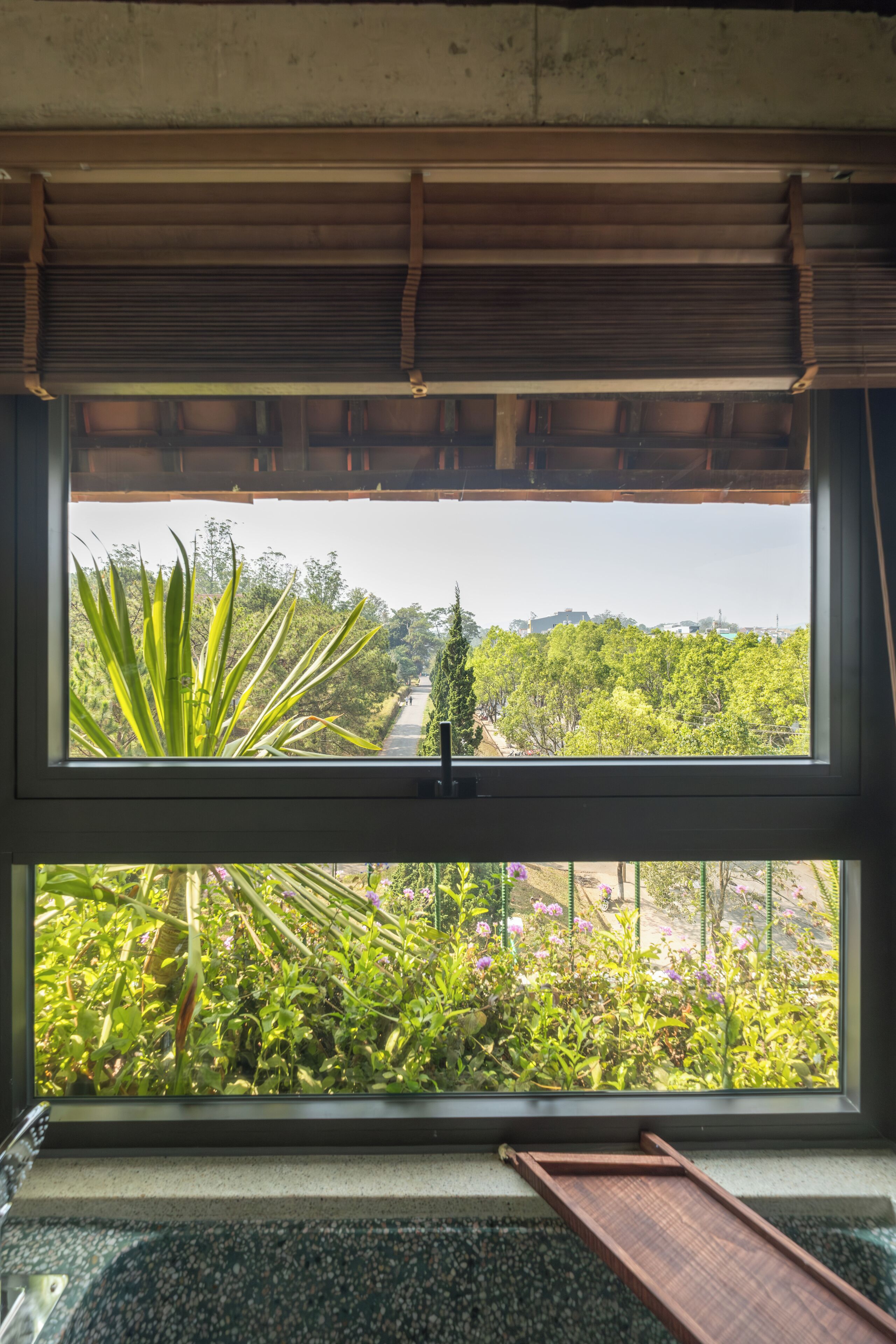 A room with a large window overlooking a garden and a pathway.