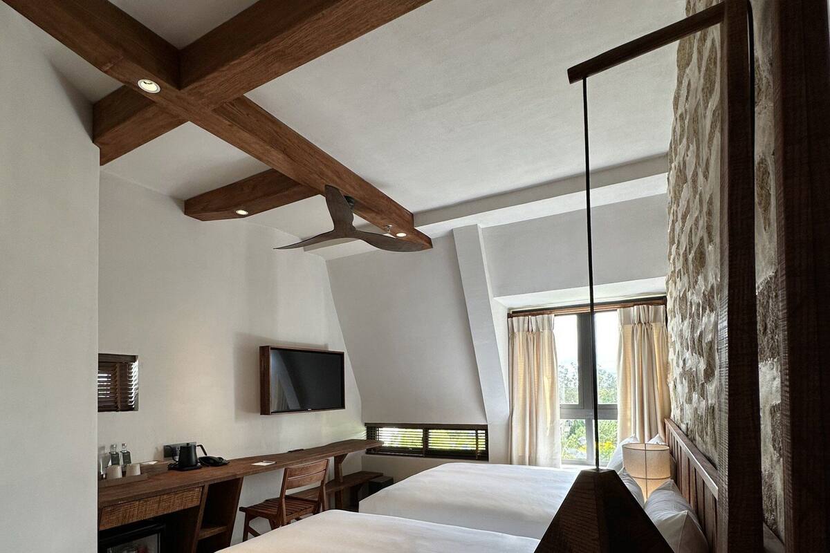 A modern hotel room with a large bed, a desk with a computer, and a television.