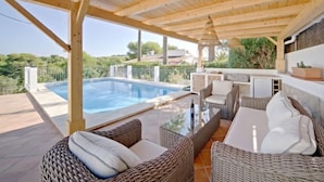 A covered outdoor area with a pool, wicker furniture, and a view of the surrounding landscape. - Vacation home Aika by Interhome (Jávea)