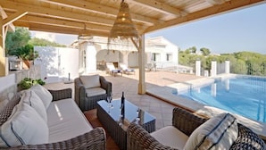 A covered outdoor area with wicker furniture, a glass table, and a pool. - Vacation home Aika by Interhome (Jávea)