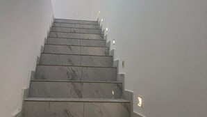 Una escala moderna amb nos de marbre i il·luminació encastrada.