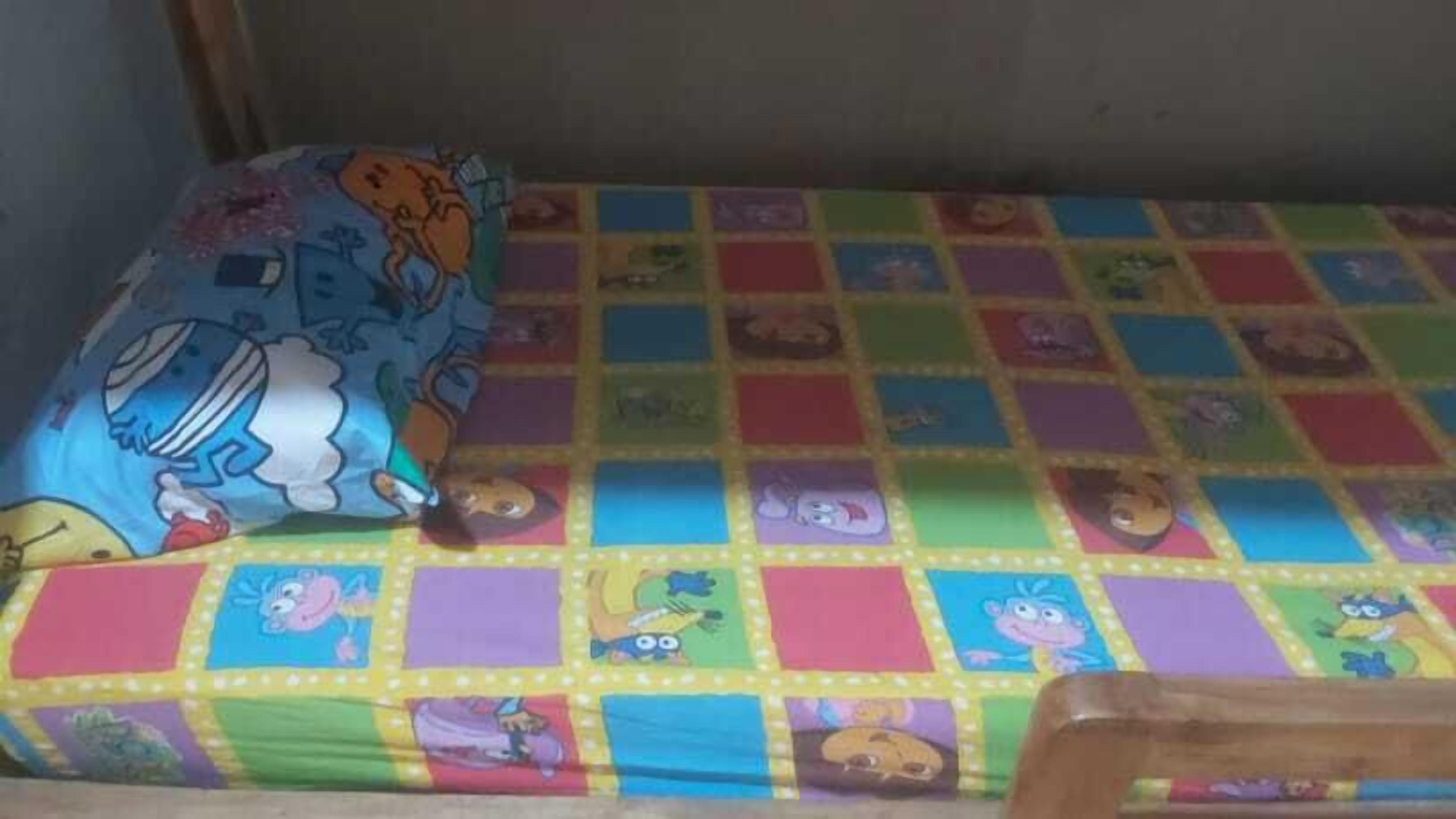 A bed with a colorful quilt featuring cartoon characters.