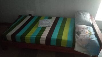 Una cama individual con una colcha a rayas y una almohada.