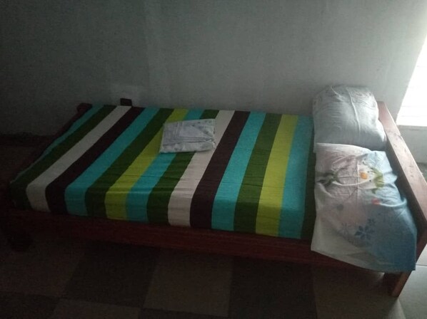 A single bed with a striped bedspread and a pillow.