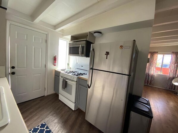 A compact kitchen with a refrigerator, microwave, stove, and oven.