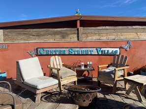 A patio area with wooden chairs and a small table, a sign reading "Center Street Villas", and a butterfly decoration.
