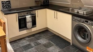 A compact kitchen with a built-in oven, a washing machine, and a toaster. - Central location 2-Bed Apartment in Maidstone (Maidstone)