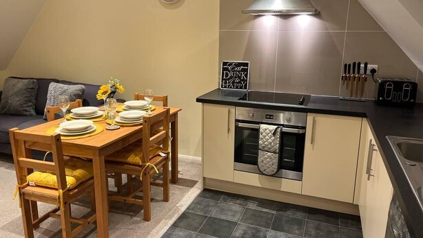 A compact kitchen with a dining area, equipped with a stove, oven, and sink. - Central location 2-Bed Apartment in Maidstone (Maidstone)