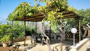 A covered outdoor seating area with a pergola, a grill, and a potted plant. - Apartment Giove by Interhome (Torre Vado)