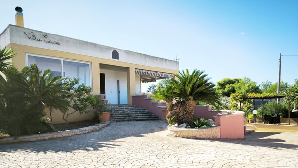 A building with a sign reading "Villa Cosimo," a paved courtyard with stone tiles, and various potted plants. - Apartment Giove by Interhome (Torre Vado)