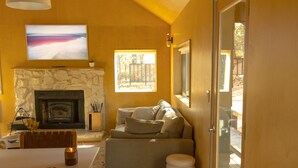A living room with a stone fireplace, a television mounted above it, and a sofa with cushions. - Colorado Lodge Big Bear California / C4 (Big Bear Lake)