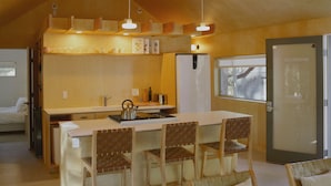 A compact kitchen with a central island, wooden chairs, a refrigerator, and a window. - Colorado Lodge Big Bear California / C4 (Big Bear Lake)