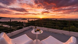 A terrace with a sunset view, a table with a bottle and fruits, and white chairs. - Villa Gordan with private Pool, Dragove, Croatia (Dragove)