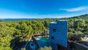 A modern building with a stone facade, surrounded by lush greenery and a clear blue sky. - Villa Gordan with private Pool, Dragove, Croatia (Dragove)