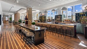 A spacious bar area with a long counter, multiple bar stools, and a view of the sky through large windows. - Luxury ocean and sunset views from spacious condo in Palm Beach Resort and Spa 1802 (Singer Island)
