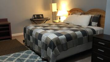 A bedroom with a bed, a nightstand, a lamp, a desk, and a chair.