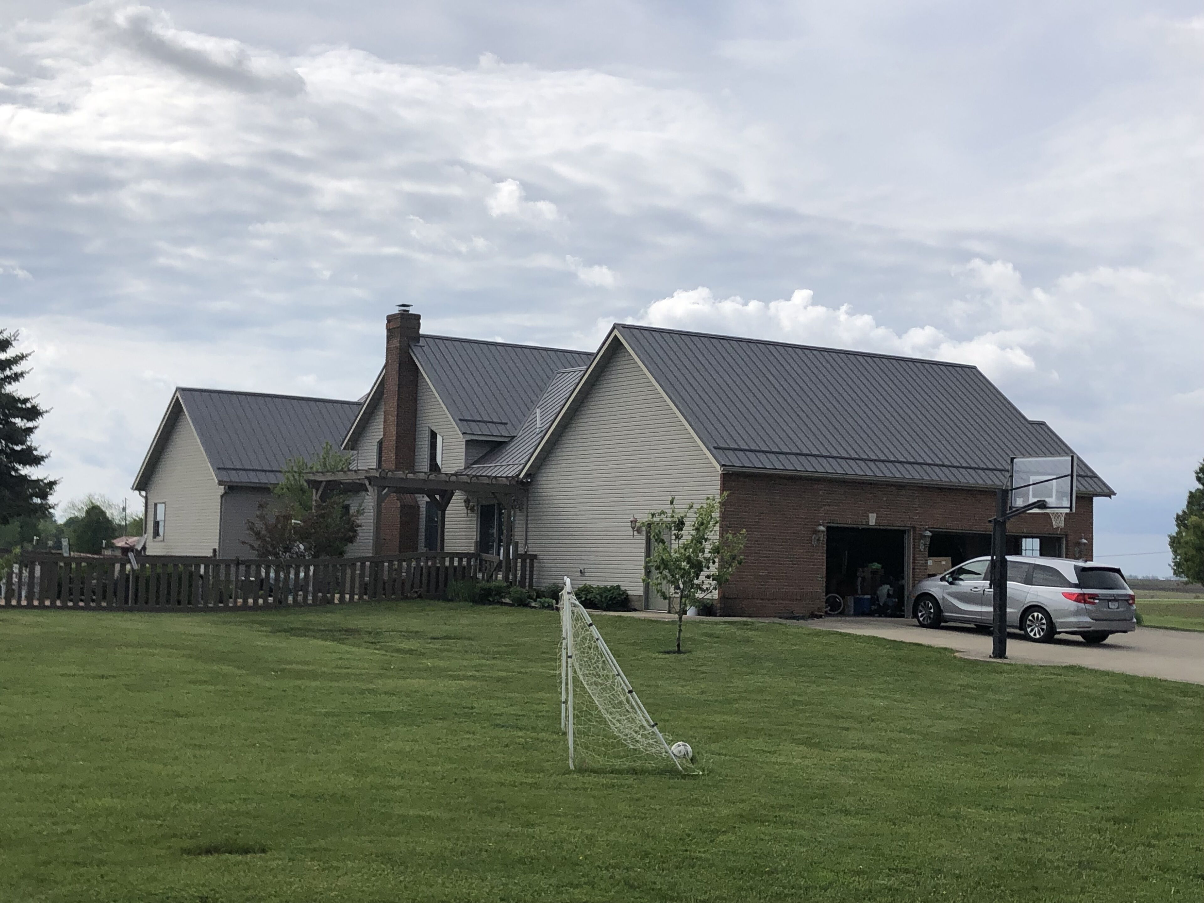 A residential area with a house, a basketball hoop, and a car parked in front.