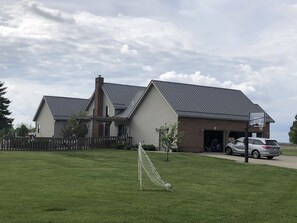A residential area with a house, a basketball hoop, and a car parked in front.