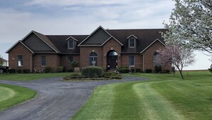 A large brick house with a driveway leading to a gated entrance.