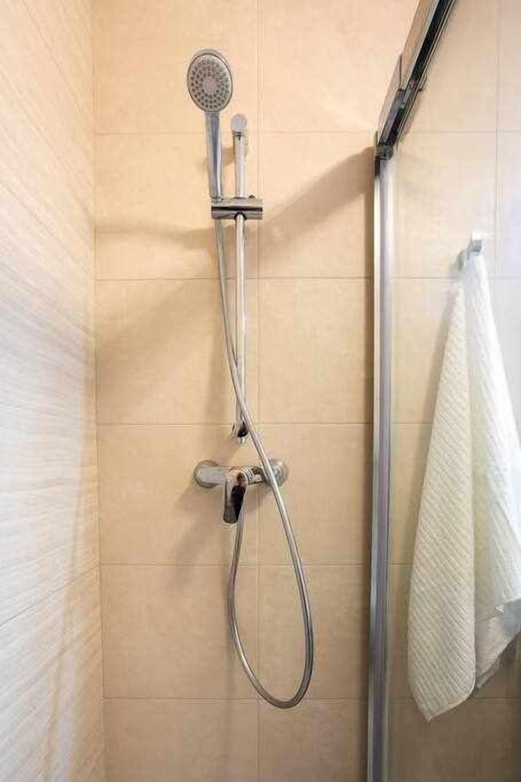 A shower with a handheld showerhead and a handheld hose.