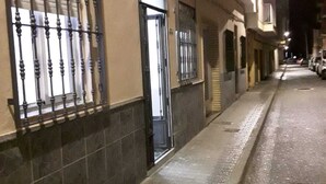 A narrow street at night with buildings on either side, featuring a gated entrance and a tiled facade.
