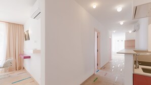 Et moderne hotelværelse med tekøkken, siddeområde med stol og stort vindue med gardiner.
