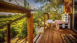 Une terrasse en bois avec un banc et une table, offrant une vue sur un paysage verdoyant et luxuriant.
