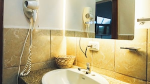 A bathroom with a granite countertop, a white sink, a hairdryer, and a mirror. - Hotel el Campanario (Comayagua)